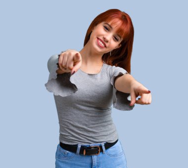 Genç Kızıl saçlı kız puan parmak size mavi zemin üzerine