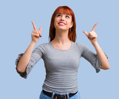 İşaret parmağı ile mavi arka plan üzerinde harika bir fikir genç Kızıl saçlı kız