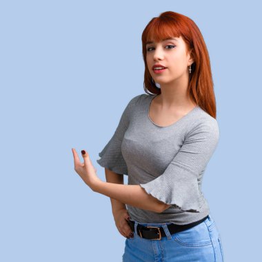 Geri mavi zemin üzerine işaret parmağı ile işaret eden genç Kızıl saçlı kız