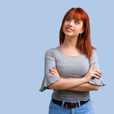 Genç Kızıl saçlı kız stand ve mavi arka plan üzerinde seyir