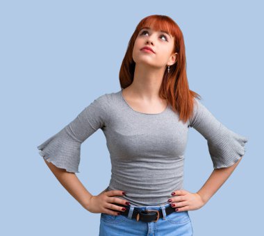 Genç Kızıl saçlı kız stand ve mavi arka plan üzerinde seyir