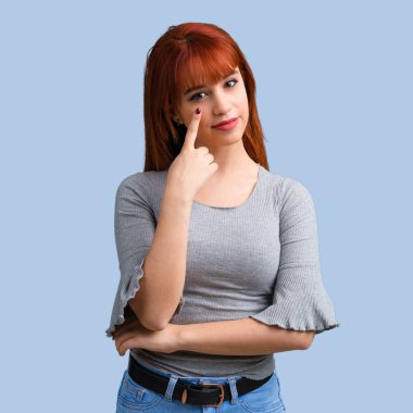 Ayakta ve önüne mavi arka plan üzerinde seyir genç Kızıl saçlı kız