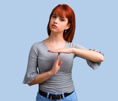 Genç Kızıl saçlı kız yapma dur jest elinde mavi arka plan ile