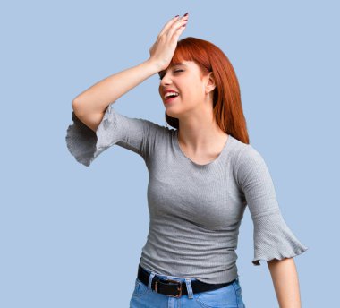 İsteyen genç Kızıl saçlı kız çözüm üzerinde mavi arka plan gerçekleştirmektedir.