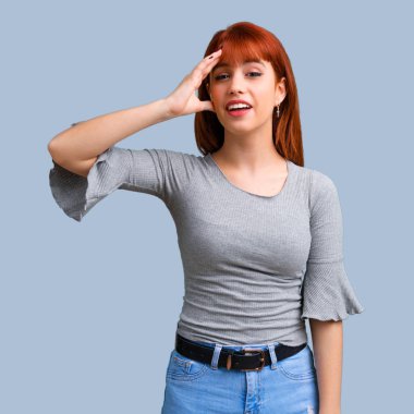 İsteyen genç Kızıl saçlı kız çözüm üzerinde mavi arka plan gerçekleştirmektedir.