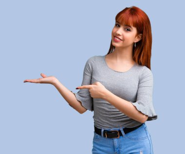 Mavi arka plan üzerinde Palm'da boşaltmak hayali tutan genç Kızıl saçlı kız