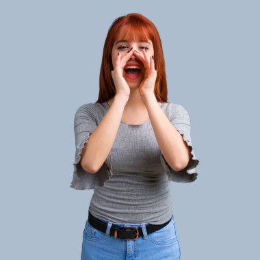 Üzerinde mavi arka plan açık ağız ile bağırarak genç Kızıl saçlı kız