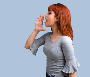 Üzerinde mavi arka plan açık ağız ile bağırarak genç Kızıl saçlı kız