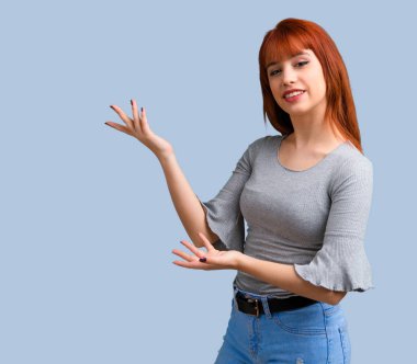 Sunulması ve mavi zemin üzerine gelmek için davet genç Kızıl saçlı kız