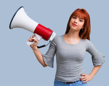 Mavi arka plan üzerinde bir megafon ile bağırarak genç Kızıl saçlı kız