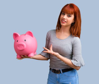 Mavi arka plan üzerinde büyük bir servet tutan genç Kızıl saçlı kız