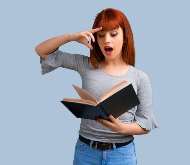Holding ve mavi arka plan ile ilgili bir kitap okuma genç Kızıl saçlı kız