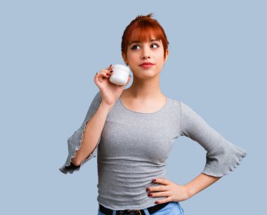 Mavi arka plan üzerinde nemlendirici ile genç Kızıl saçlı kız