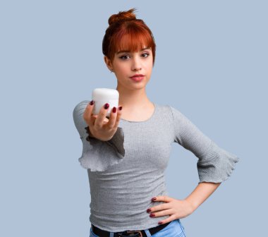 Mavi arka plan üzerinde nemlendirici ile genç Kızıl saçlı kız