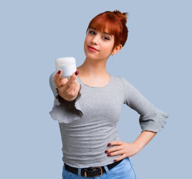 Mavi arka plan üzerinde nemlendirici ile genç Kızıl saçlı kız