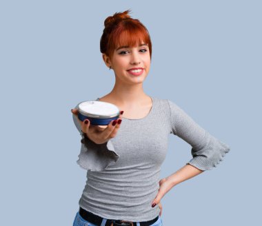 Mavi arka plan üzerinde nemlendirici ile genç Kızıl saçlı kız