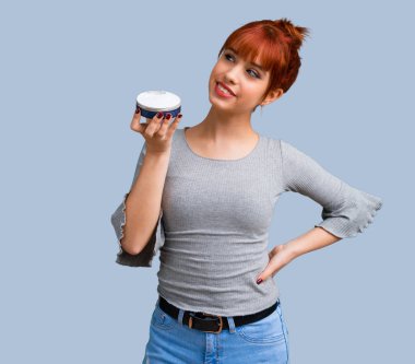 Mavi arka plan üzerinde nemlendirici ile genç Kızıl saçlı kız