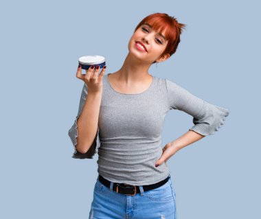 Mavi arka plan üzerinde nemlendirici ile genç Kızıl saçlı kız