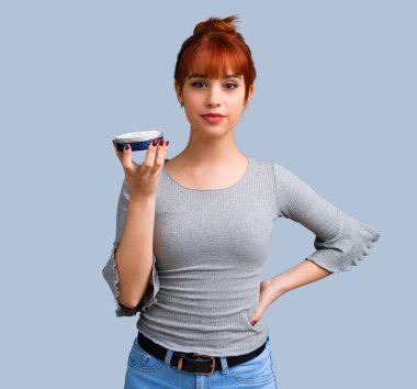 Mavi arka plan üzerinde nemlendirici ile genç Kızıl saçlı kız