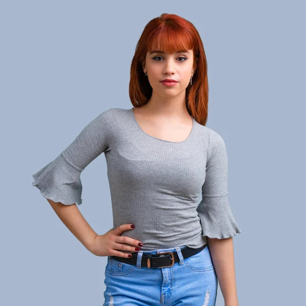 Silah, kalça üzerinde mavi arka plan ile poz genç Kızıl saçlı kız