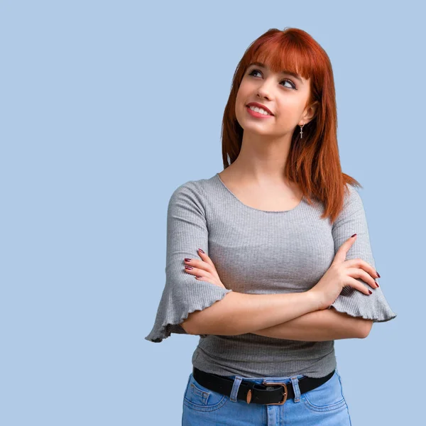 Genç Kızıl saçlı kız stand ve mavi arka plan üzerinde seyir