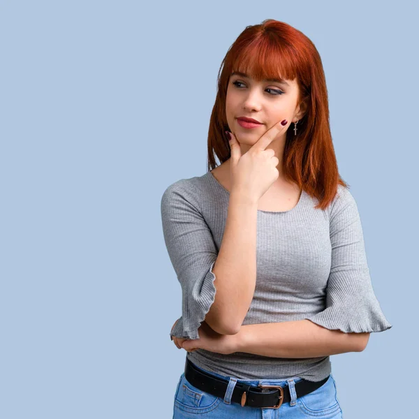 Ayakta ve yan üzerinde mavi arka plan arıyorum genç Kızıl saçlı kız
