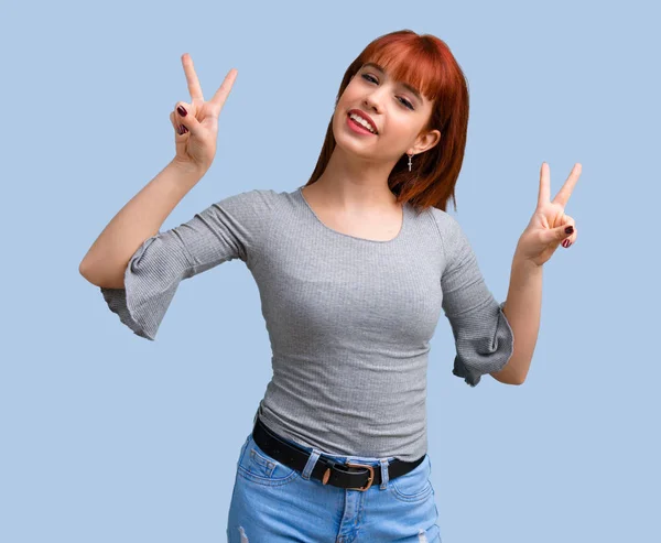 Menina Ruiva Jovem Sorrindo Mostrando Sinal Vitória Fundo Azul — Fotografia de Stock