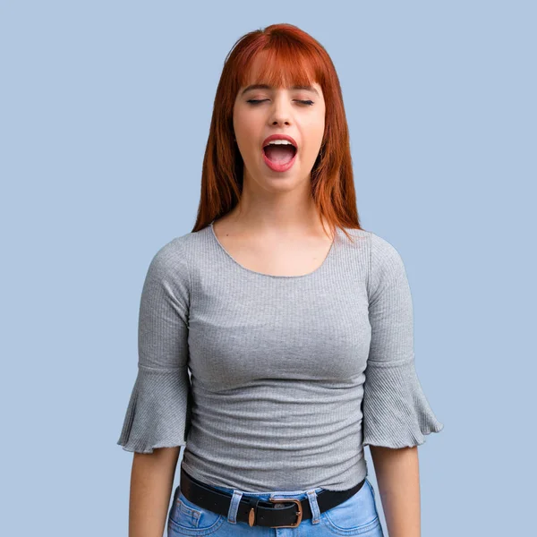 Üzerinde mavi arka plan açık ağız ile bağırarak genç Kızıl saçlı kız