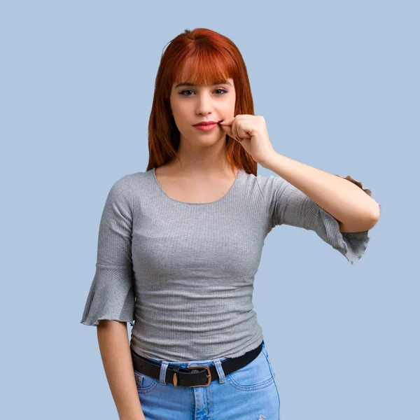 Ağız ve sessizlik bir jest mavi arka plan üzerinde kapanış bir işaret gösteren genç Kızıl saçlı kız