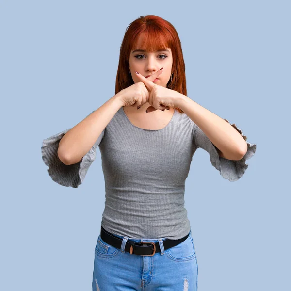 Ağız ve sessizlik bir jest mavi arka plan üzerinde kapanış bir işaret gösteren genç Kızıl saçlı kız