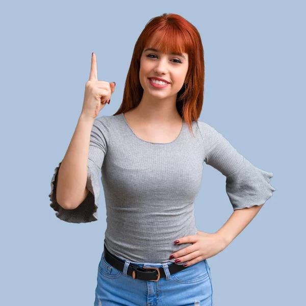 Mavi arka plan üzerinde bir numara işareti sayma genç Kızıl saçlı kız