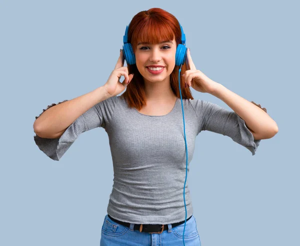 Jonge Roodharige Meisje Luisteren Naar Muziek Met Koptelefoon Blauwe Achtergrond — Stockfoto