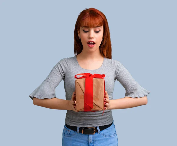 Joven Pelirroja Sosteniendo Regalo Sobre Fondo Azul —  Fotos de Stock