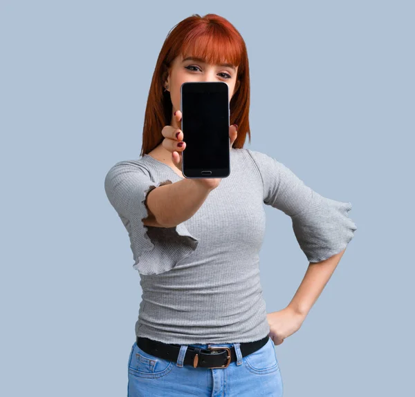 青の背景に携帯電話を使用して若い赤毛の女の子 — ストック写真