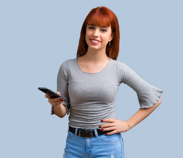 青の背景に携帯電話を使用して若い赤毛の女の子 — ストック写真