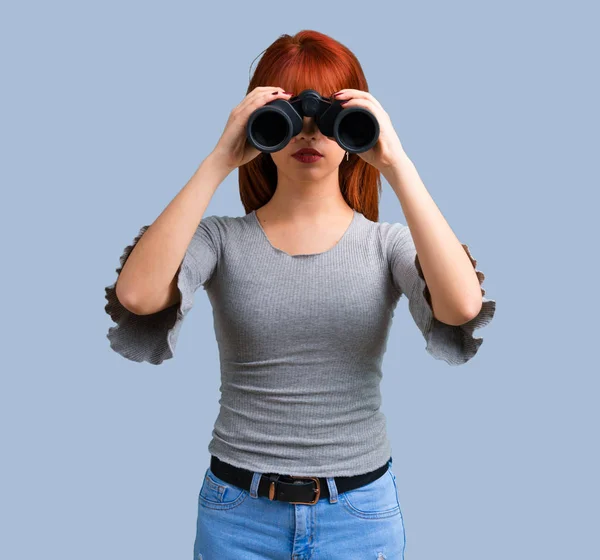 Jonge Roodharige Meisje Met Zwarte Verrekijkers Blauwe Achtergrond — Stockfoto