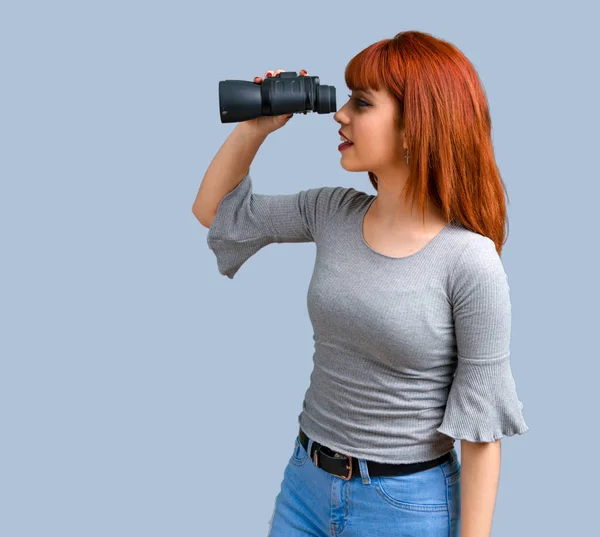 Unga Rödhårig Tjej Med Svart Kikare Blå Bakgrund — Stockfoto