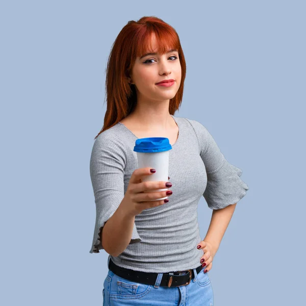 Sıcak kahve paket servisi olan restoran kağıt bardak mavi arka plan üzerinde tutan genç Kızıl saçlı kız