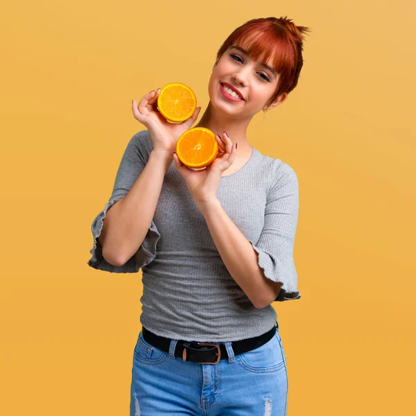 Bir portakal turuncu arka planda tutan genç Kızıl saçlı kız