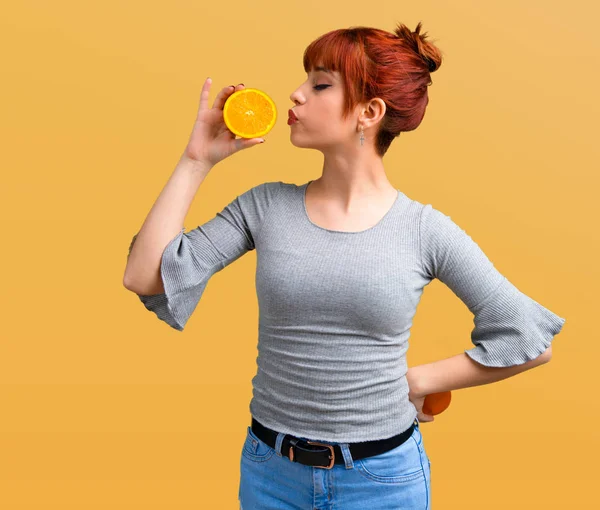 Junges Rothaariges Mädchen Hält Eine Orange Auf Orangefarbenem Hintergrund — Stockfoto