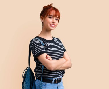 Genç öğrenci Kızıl saçlı kız silah tutmak koyu sarı arka plan üzerinde çarpı işareti