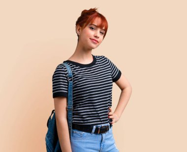 Genç öğrenci Kızıl saçlı kız kalça koyu sarı arka plan üzerinde silah ile poz