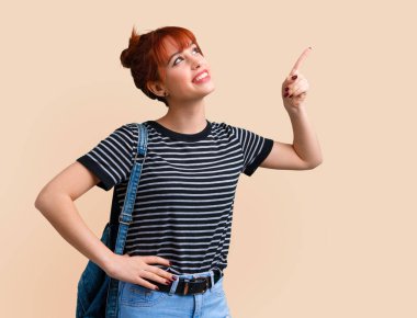 Harika bir fikir koyu sarı zemin üzerine işaret parmağı ile işaret genç öğrenci Kızıl saçlı kız