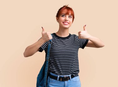 Jest Yaşasın vererek ve koyu sarı arka plan üzerinde gülümseyen genç öğrenci Kızıl saçlı kız