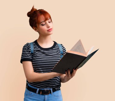 Genç öğrenci Kızıl saçlı kız koyu sarı arka plan üzerine bir kitap okuma