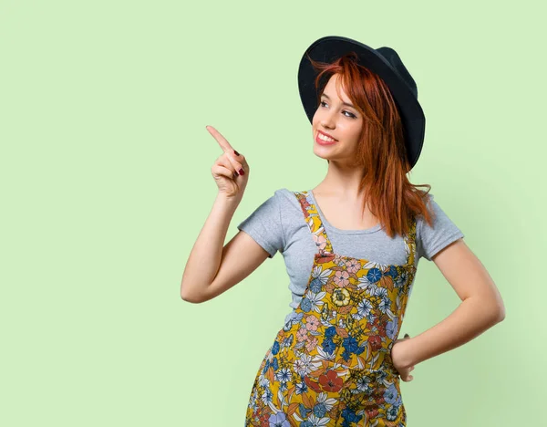 Güzel kızıl saçlı kız tarafına parmak işaret ve bir ürün sunma şapka ile