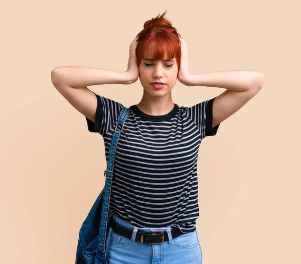 Her iki kulak koyu sarı arka plan üzerinde elleriyle kapsayan genç öğrenci Kızıl saçlı kız