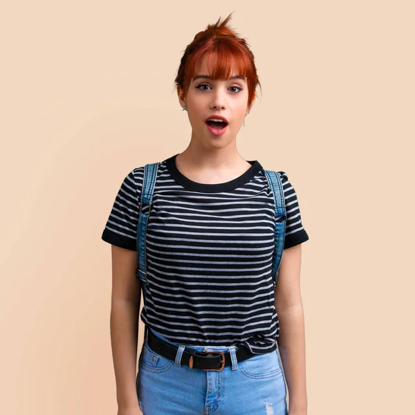 Sürpriz ve koyu sarı zemin üzerine şok yüz ifadesi ile genç öğrenci Kızıl saçlı kız