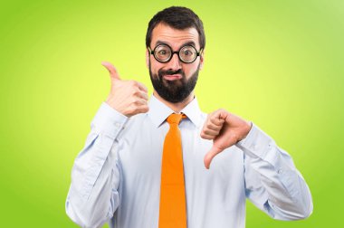 Komik adam gözlüklü renkli arka plan üzerinde iyi-kötü işaret yapma