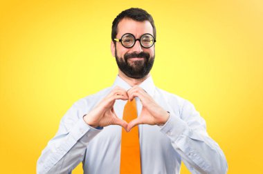 Komik adam gözlüklü renkli arka plan üzerinde elleriyle bir kalp yapma